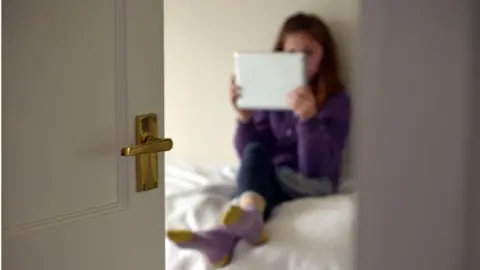 BBC Girl sitting on bed, using a tablet