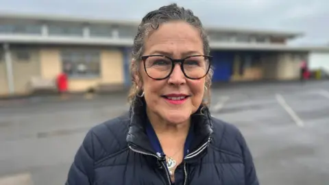 Teacher and union representative Debra de Muschamp stands smiling outside school