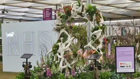 Relove Technology A tall garden sculpture with white branches with the 'RHS' sign in the background