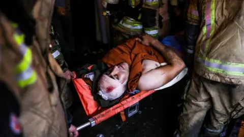 AFP/Getty Images An injured person carried on stretchers after a blast at Tehran's clinic. Photo: 30 June 2020