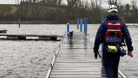 K9 Search and Rescue NI A sniffer dog and their handler search for a missing person at a lake