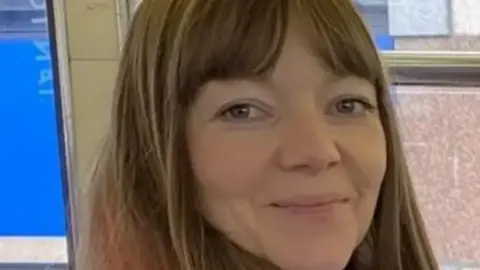 A close-up image of Joanne Samak, who has long, light brown hair and is smiling at the camera. 