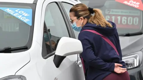 Getty Images Woman browsing cars in a showroom