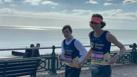 Angela Blackwell Angela Blackwell wearing a pink visor running next to Vicky Graimes along the seafront