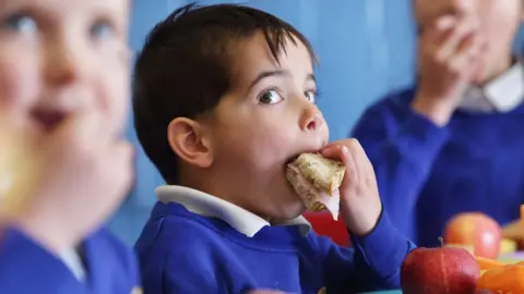 Peter Cade/Getty Images A child eating sandwiches