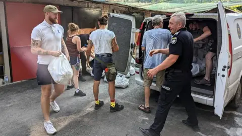 Ryan Williams Aid workers unload supplies from a van in Ukraine