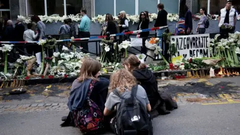 Getty Images Mourners lay flowers after mass shootings in Serbia