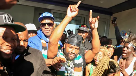 Reuters Former US boxing champion Floyd Mayweather gestures to fans upon his arrival at Robert Gabriel Mugabe International Airport in Harare, Zimbabwe - 13 July 2023