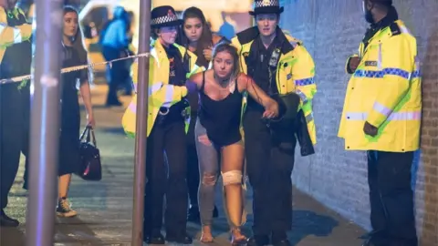Joel Goodman/LNP Eve Senior is helped to safety by two police officers following the Manchester Arena attack