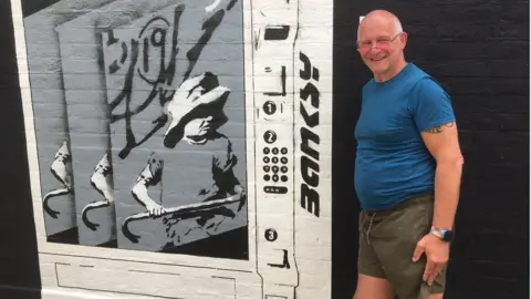 Guy Campbell/BBC Joe Thompson with his version of the Banksy mural