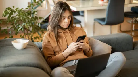 Getty Images Young woman looking at mobile phone