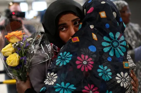 Getty Images A Yemeni woman hugs her mother at a Virginia airport in February after courts granted a stay on Trump's order