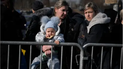  LOUISA GOULIAMAKI/AFP via Getty Images People waiting to board buses after crossing from Ukraine into Poland