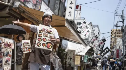 Getty Images A man stands outside a seafood restaurant in Tsujiki