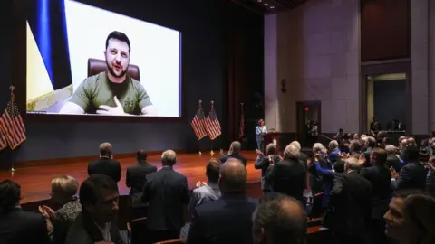 EPA Mr Zelensky appears by video screen to a standing ovation