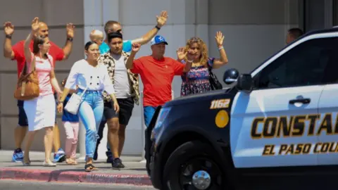 Reuters Shoppers exit with their hands up after a mass shooting at a Walmart in El Paso, Texas.