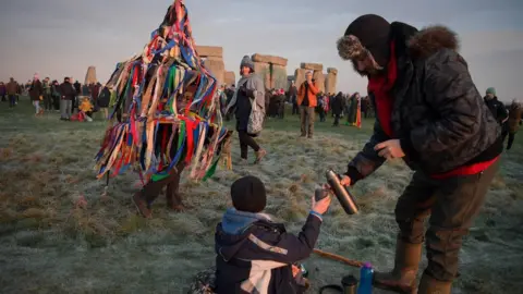 Getty Images People greet the sunrise at Stonehenge