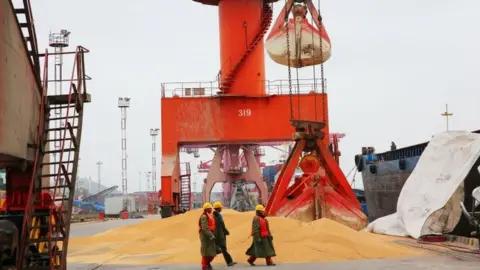 AFP Workers walk past imported soybeans at a port in Nantong in China"s eastern Jiangsu province on April 4, 2018