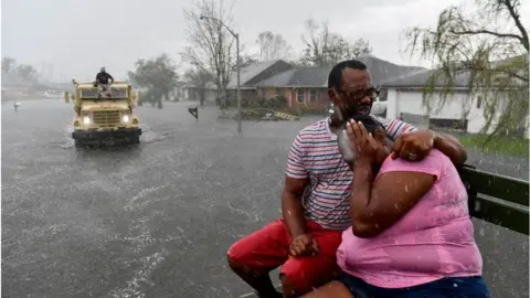 Getty Images people evacuate from a flooded neighborhood in LaPlace, Louisiana on 30 August, 2021