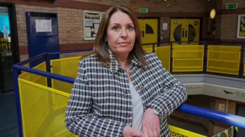 BBC/Gemma Laister Penni Allen, Safeguarding lead at Chesterfield High School, leans on a railing and looks at camera