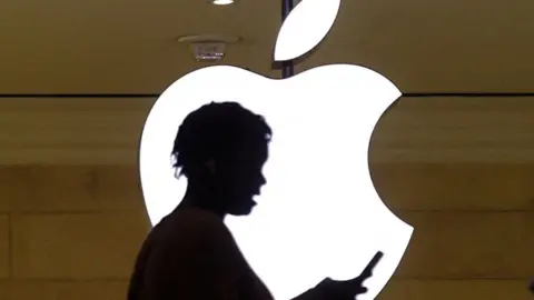 Reuters photograph of someone checking their phone infront of an apple logo