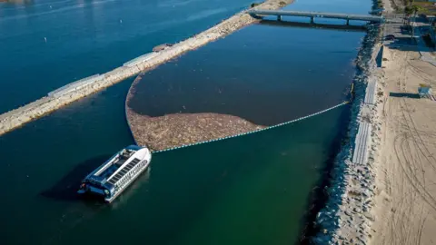 The Ocean Cleanup Rubbish accumulates behind the barrier of an Interceptor system in Ballona Creek, California