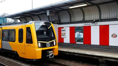 Nexus A bright yellow and black Metro train pulled up at he Stadium of Light station. The walls of the platform are made up of red and white panels with the Sunderland crest on one them.