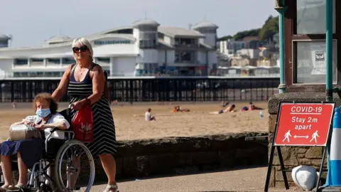 AFP Two women pass a coronavirus warning sign at Western-super-Mare