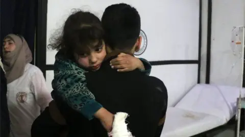 AFP/Getty Images An injured girl is carried at a makeshift clinic in Douma, Syria