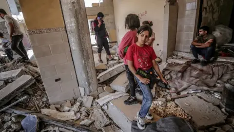 EPA Palestinian girls stand at the rubble of their destroyed house in Gaza