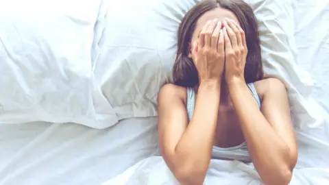 Young woman in bed trying to sleep