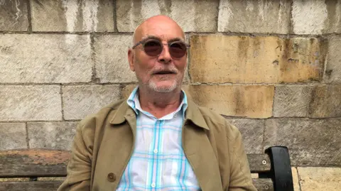 BBC / Naj Modak Man sat on bench