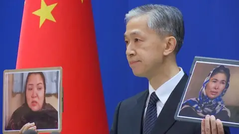 Reuters Chinese Foreign Ministry spokesman Wang Wenbin holds pictures while speaking during a news conference in Beijing, China February 23, 2021,