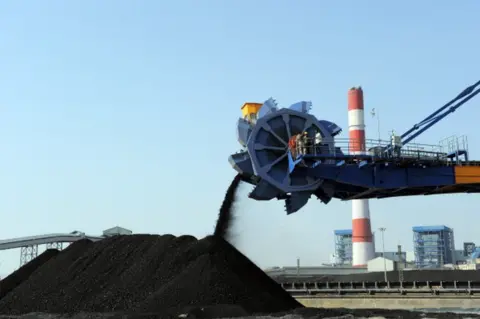 AFP Workers use heavy machinery to sift through coal at the Adani Power company thermal power plant at Mundra some 400 kms from Ahmedabad on February 18, 2011.