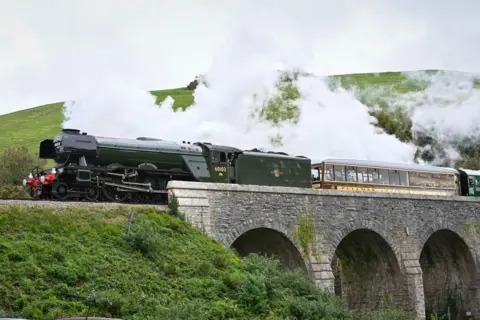 Getty Images Flying Scotsman pulling a train over a bridge on the Swanage Railway on October 22 2022