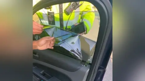 Essex Police Police officers taking a blackout film off a vehicle