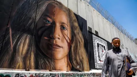 AFP A Palestinian walks past a mural painted on Israel's controversial separation barrier in the West Bank city of Bethlehem on July 29, 2018