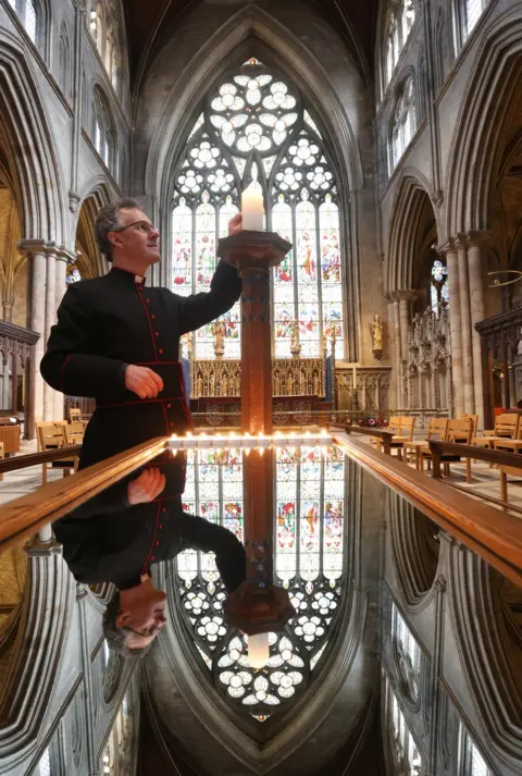 Reuters The Dean of Ripon lights a large candle in a cathedral