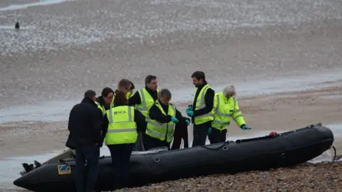 Susan Pilcher National Crime Agency officers examine a boat at Greatstone beach in Kent that arrived carrying 12 migrants on 31 December 2018