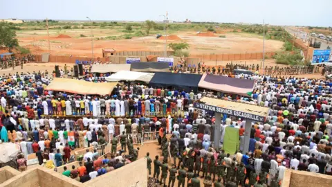 Mahamadou Hamidou/Reuters Nigerien protesters pray outside a French army base