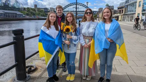NewcastleGateshead Initiative Members of a Ukrainian choir with Newcastle Cllr Alex Hay on the city's quayside