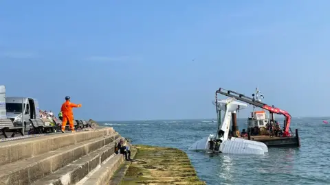 Crane lifting plane out of water