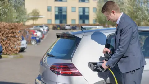 Getty Images Man charging car at work