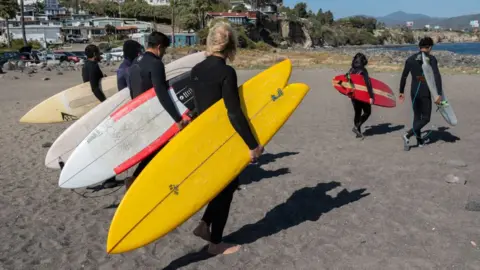 Getty Images Surfers head to the sea in honour of the three foreign surfers murdered in Ensenada