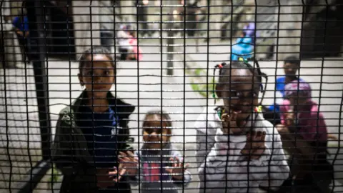 BBC/Shiraaz Mohamed Children by a fence in Manenberg, Cape Town - South Africa