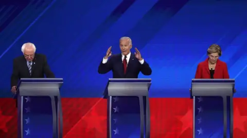 Win McNamee/Getty Images Mr Sanders, Mr Biden and Ms Warren on stage at the Houston debate in September