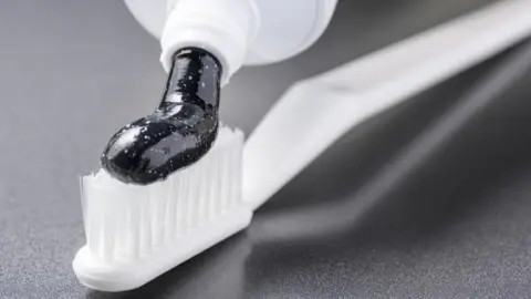 Getty Images Toothpaste containing charcoal on a toothbrush