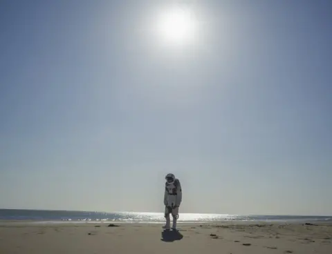 Cao Fei A photo by Cao Fei showing an astronaut walking on an empty beach