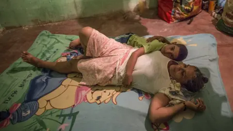 Glenna Gordon/Save the Children Diego cuddles his Grandma on a Winnie the Pooh blanket on the floor