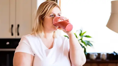 Getty Images A woman on a diet drinking a smoothie (posed model)